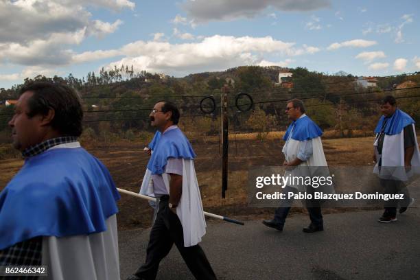 People walk past a burnt electric post during the funeral of a victim of a wildfire in the village of Vila Nova, near Vouzela on October 17, 2017 in...