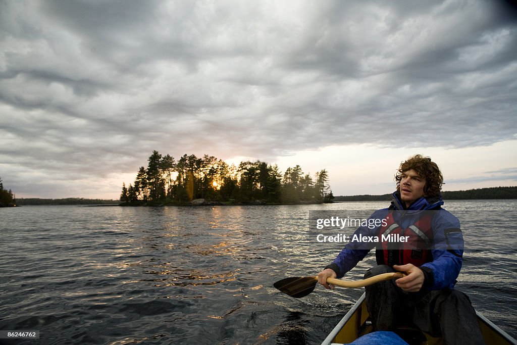 Man canoeing at sunset on a lake.