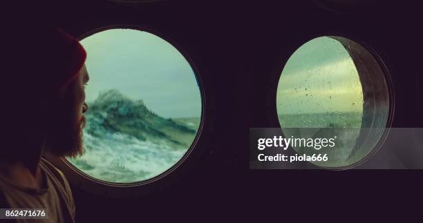 man op de patrijspoort venster van een vaartuig in een ruwe zee - patrijspoort stockfoto's en -beelden