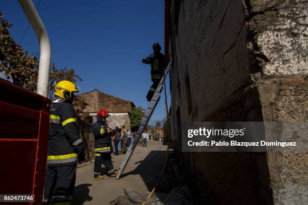 Firefighters enter to a burning house through a window to extinguish the fire in the village of Travanca do Mondego on October 17, 2017 in Coimbra...