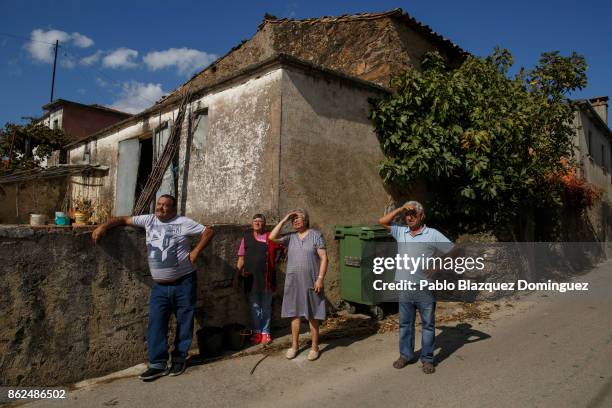 Villagers watch as firefighters try to extinguish a burning house in the village of Travanca do Mondego on October 17, 2017 in Coimbra region,...