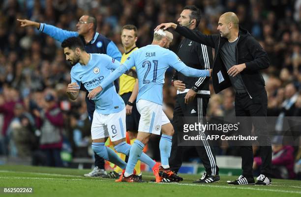 Manchester City's Spanish manager Pep Guardiola taps Manchester City's Spanish midfielder David Silva on the head as he is substituted for Manchester...