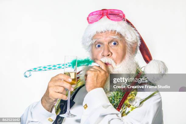 funny santa claus celebrating with a glass of champagne and blowing a party blowout - kerstman cool stockfoto's en -beelden