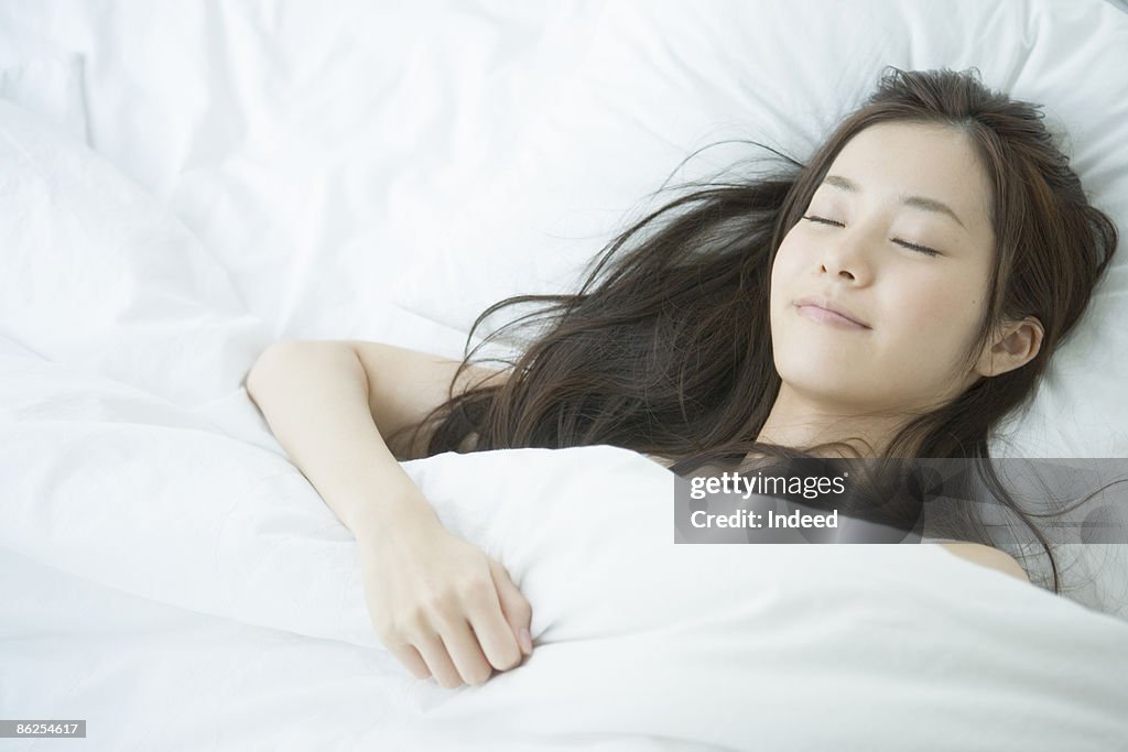 Young woman sleeping on bed, portrait