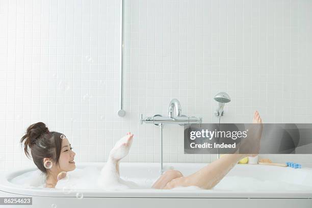 young woman taking a bubble bath, scooping bubble - japanese women bath stock pictures, royalty-free photos & images