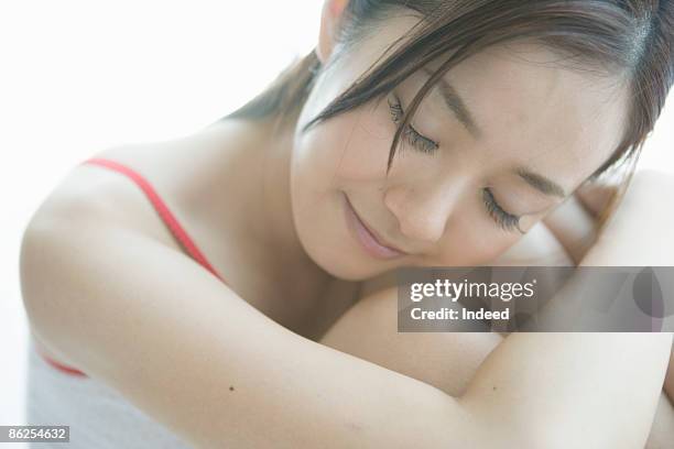 young woman wrapping around knee, eyes closed - hugging knees stock pictures, royalty-free photos & images