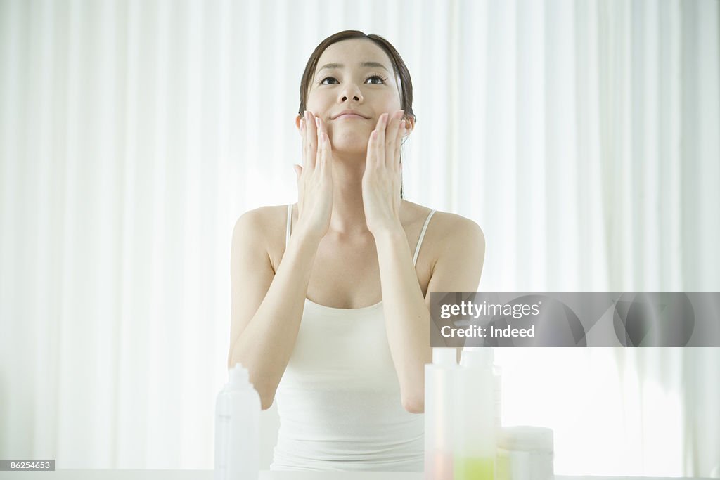 Young woman applying facial cream