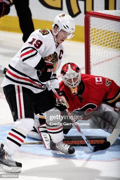 Miikka Kiprusoff of the Calgary Flames puts his paddle on the ice while Jonathan Toews of the Chicago Blackhawks skates in front of the net during...