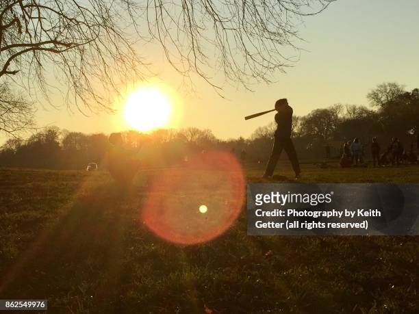 pitch, hit, and catch: youngsters playing with a baseball on a field in a park in late afternoon under a setting sun - batting sports activity - fotografias e filmes do acervo