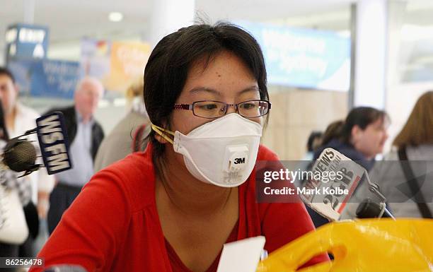 Traveller wearing a mask is asked questions by the media on arrival at the Sydney International airport on April 28, 2009 in Sydney, Australia. Swine...
