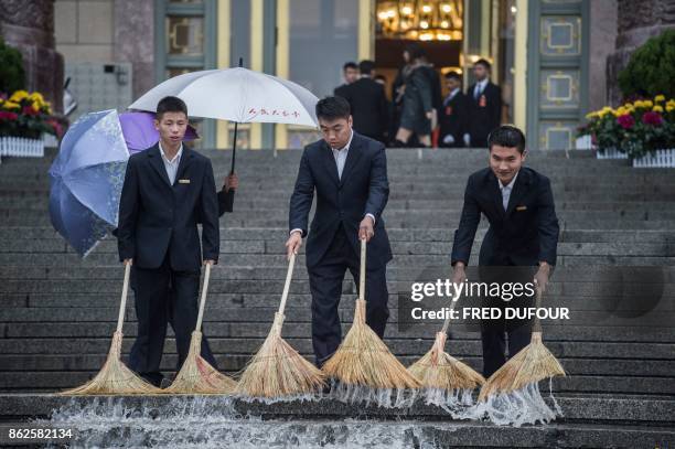 Chinese security guards sweep water at the start of the Communist Party's 19th Congress in Beijing on October 18, 2017. The Chinese Communist Party...
