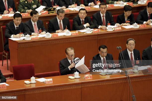 Jiang Zemin, China's former president, front row left, holds a magnifying glass while reading as he sits alongside Li Keqiang, China's premier, and...