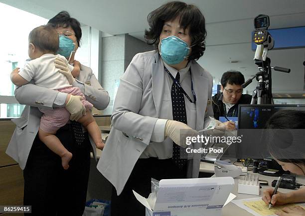 South Korean quarantine officers take samples from a baby who arrived from the US at Incheon International Airport on April 28, 2009 in Incheon,...