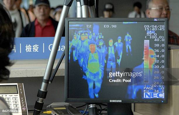 South Korean quarantine officer monitors a thermal scanner as passengers from an international flight arrive at Incheon International Airport on...