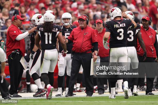 Head coach Bruce Arians of the Arizona Cardinals talks with wide receiver Larry Fitzgerald and quarterback Carson Palmer during the first half of the...