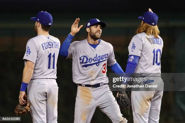 Logan Forsythe, Chris Taylor, and Justin Turner of the Los Angeles Dodgers celebrate after beating the Chicago Cubs 6-1 during game three of the...