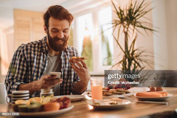 gelukkig man van het tekstoverseinen op mobiele telefoon tijdens ontbijt. - 2017 common good forum stockfoto's en -beelden