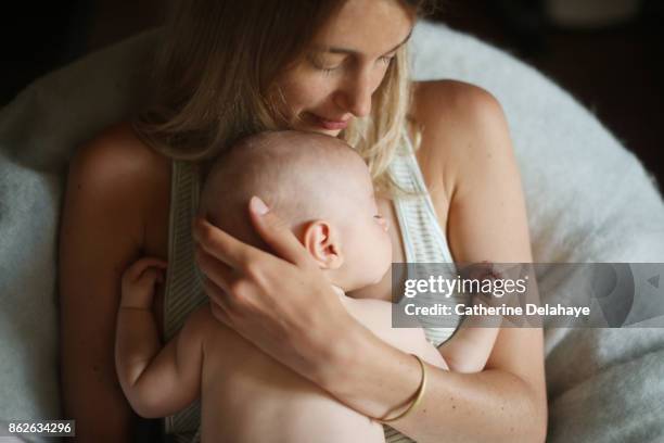 a 3 months old baby boy sleeping in the arms of his mum - baby and mother fotografías e imágenes de stock