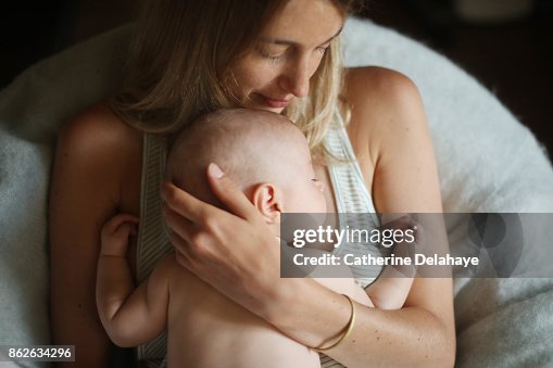A 3 months old baby boy sleeping in the arms of his mum A 3 months old baby boy sleeping in the arms of his mum