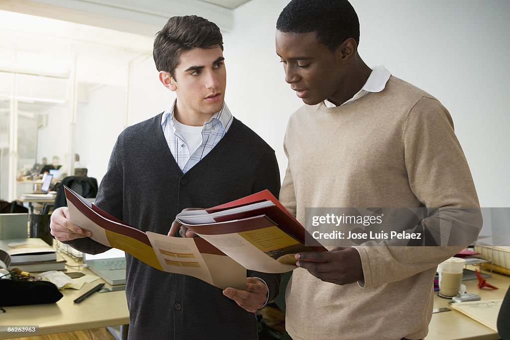 Two young business partners looking at reports