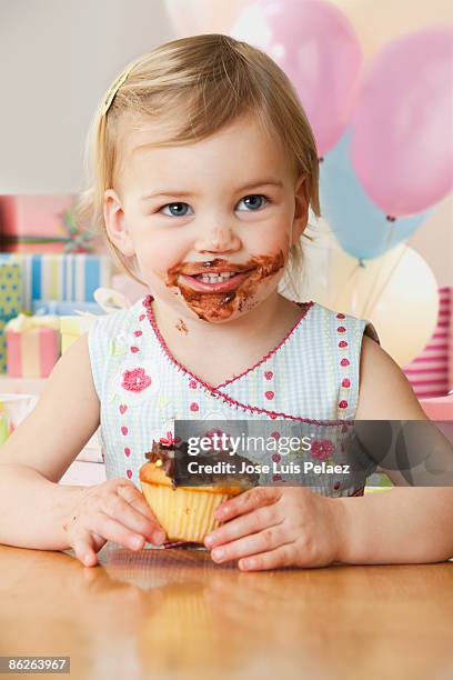 toddler girl eating chocolate frosted  - one baby girl only fotografías e imágenes de stock