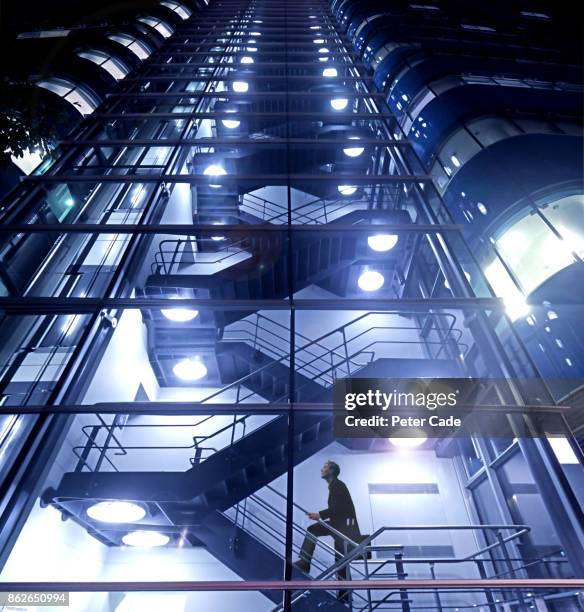 man climbing stairs in high rise building - stairs business stock pictures, royalty-free photos & images