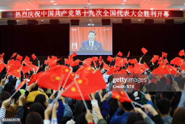 College students wave national flags as they watch the opening of the 19th Communist Party Congress in Huaibei in China's eastern Anhui province on...