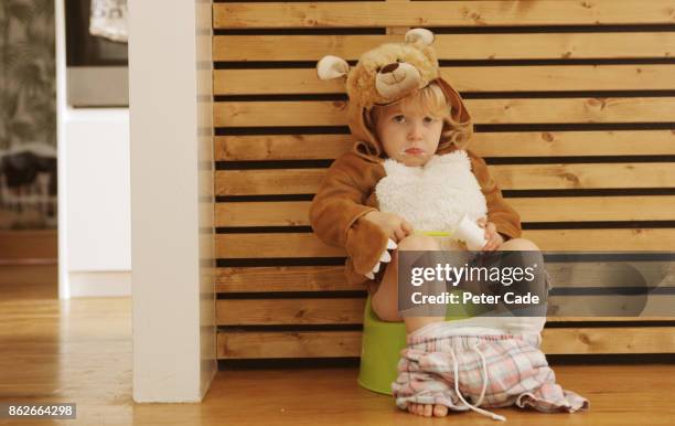 toddler eating yogurt while sat on a potty dressed as a bear - bear suit 個照片及圖片檔