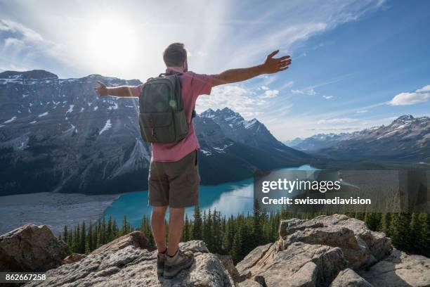 hiker male reaches mountain top, arms outstretched - peyto lake stock pictures, royalty-free photos & images