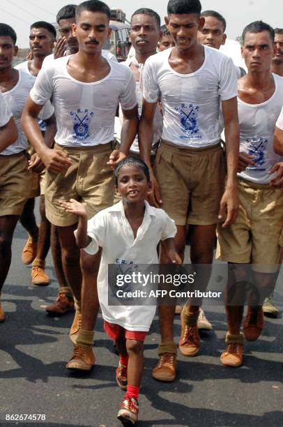 Indian child Budhia Singh is accompanied by soldiers of India's Central Reserve Police Force as he runs along a road on the outskirts of Bhubaneswar,...