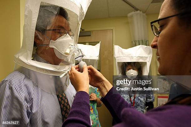 Karya Lustig sprays a chemical mist into a hood as she fits and trains doctors and nurses on how to use the N95 respiratory mask at the La Clinica...