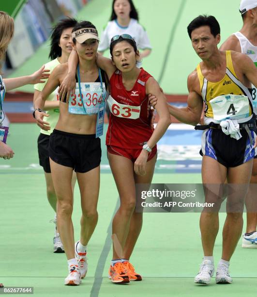 An exhausted athlete is helped by colleagues after crossing the finish line during the Hong Kong Marathon on February 8, 2009. Cyprian Kiogora Mwobi...