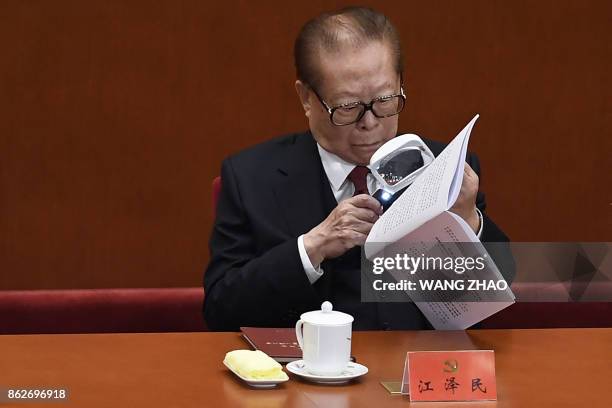 China's former president Jiang Zemin reads the script of a speech as he attends the opening session of the Chinese Communist Party's Congress at the...