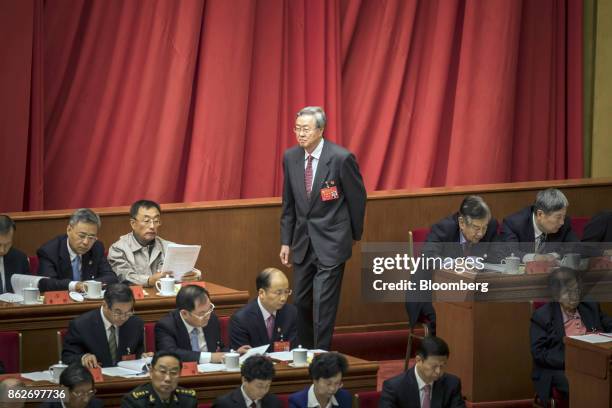 Zhou Xiaochuan, governor of the People's Bank of China, walks past other delegates during the opening of the 19th National Congress of the Communist...