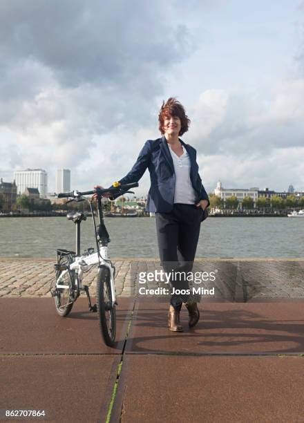businesswoman with her folding bike, portrait - tossing hair facing camera woman outdoors stock pictures, royalty-free photos & images