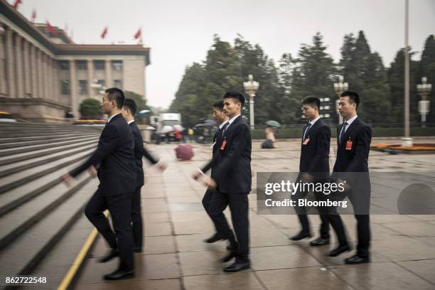 Security personnel walk towards the Great Hall of the People after the opening ceremony of the 19th National Congress of the Communist Party of China...