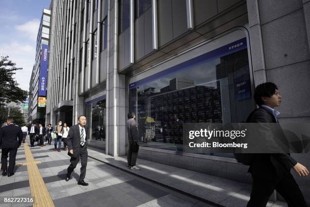 Pedestrian looks at an electronic stock board while others people walk by outside a securities firm in Tokyo, Japan, on Wednesday, Oct. 18, 2017. As...