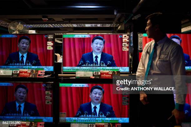 An electronics shop employee in Hong Kong on October 18, 2017 looks at television sets showing a news report on China's President Xi Jinping's speech...
