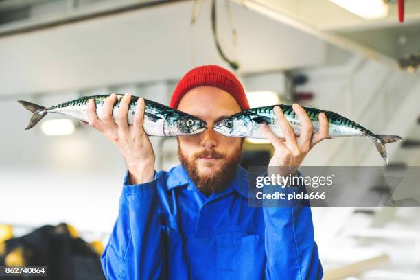 pescatore con pesce fresco sul ponte della barca da pesca - industria della pesca foto e immagini stock