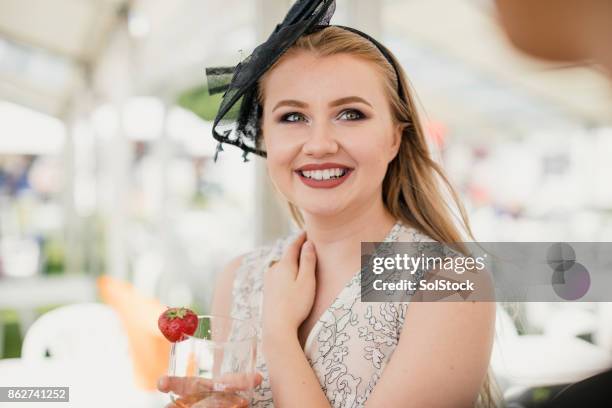 hembra joven disfrutando de una copa de vino - fascinator fotografías e imágenes de stock