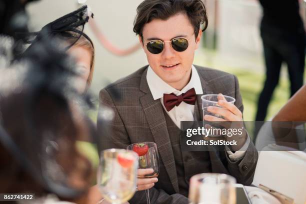 young trendy male drinking in a marquee - fascinator stock pictures, royalty-free photos & images