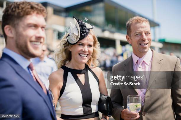 friends enjoying a drink at the races - fascinator stock pictures, royalty-free photos & images