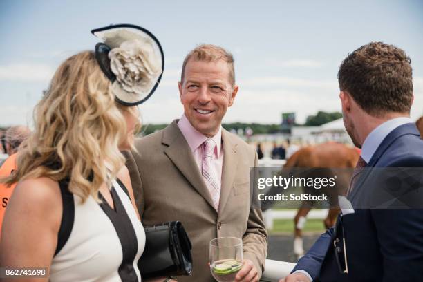 friends enjoying drinks at the race course - fascinator stock pictures, royalty-free photos & images