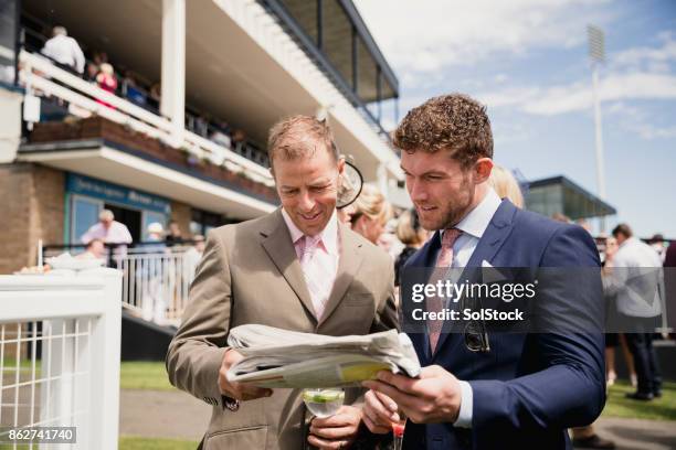 two males looking at a newspaper - horse races stock pictures, royalty-free photos & images