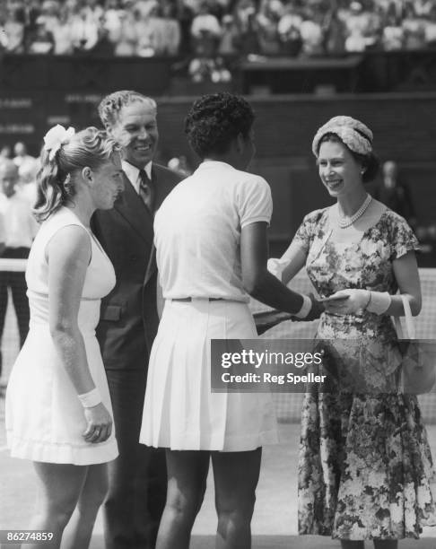 Queen Elizabeth II presents the trophy to American tennis player Althea Gibson after she won the Women's Singles final at Wimbledon, 6th July 1957....