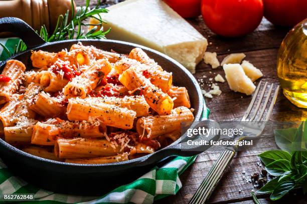 pasta in een gietijzeren pan geschoten op rustieke houten tafel - tomatensaus stockfoto's en -beelden