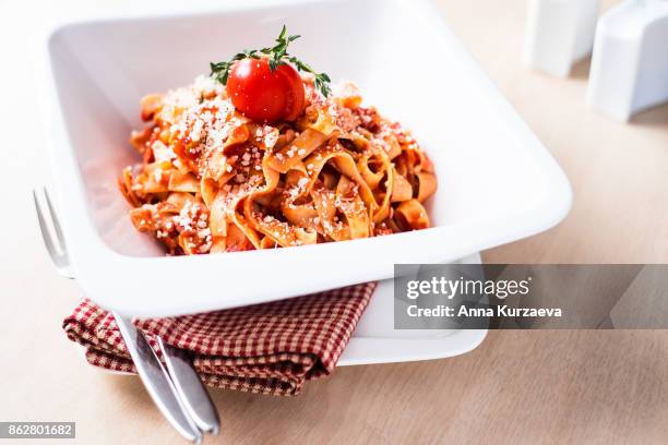 homemade classic pasta tagliatelle with traditional italian bolognese sauce or ragu from minced pork and beef meat, carrot, celery, tomatoes served with freshly grated parmesan cheese, cherry tomato and fresh thyme in a plate, selective focus - tagliatelle stock pictures, royalty-free photos & images