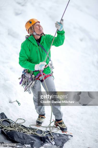 strong ice climber female holding a hope on the snow. - groen jak stockfoto's en -beelden