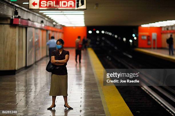 Women wears a surgical mask, to help prevent being infected with the swine flu, as she waits for the subway on April 29, 2009 in Mexico City, Mexico....