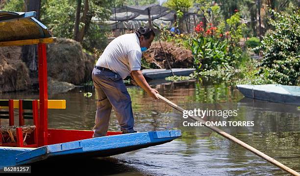 Rower in his "Trajineras", wearing a face mask triying to prevent contagion of the swine flu in one of the almost empty Xochimilco's canals in Mexico...
